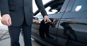 Kierowca Ubera otwierający drzwi czarnego samochodu przed kursem