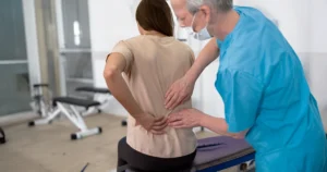 Lekarz badający ból pleców u pacjentki po urazie w pracy