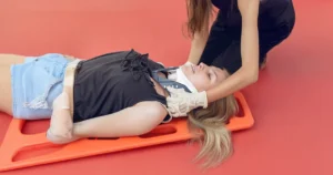 Kobieta z urazem kręgosłupa szyjnego leżąca na desce ortopedycznej