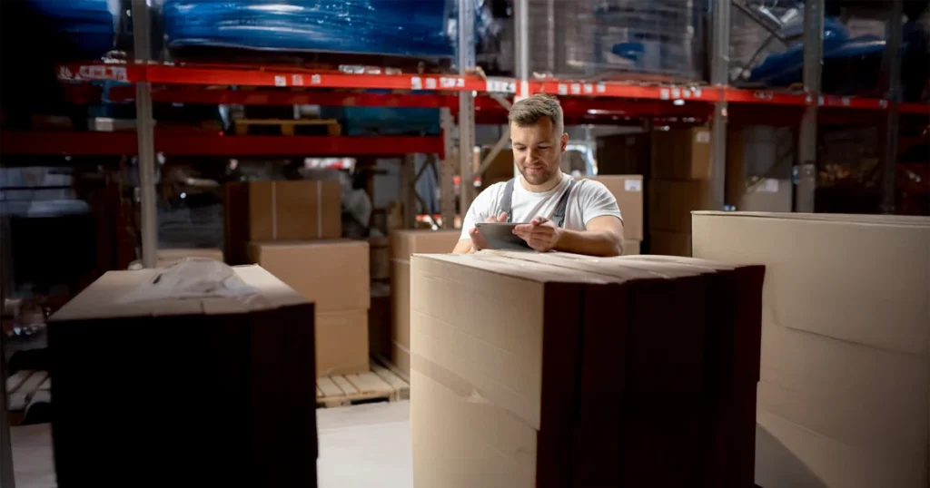 Pracownik magazynu skanujący paczki w hali Amazon – środowisko pracy logistycznej